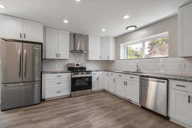 kitchen featuring white cabinets, wall chimney range hood, and appliances with stainless steel finishes