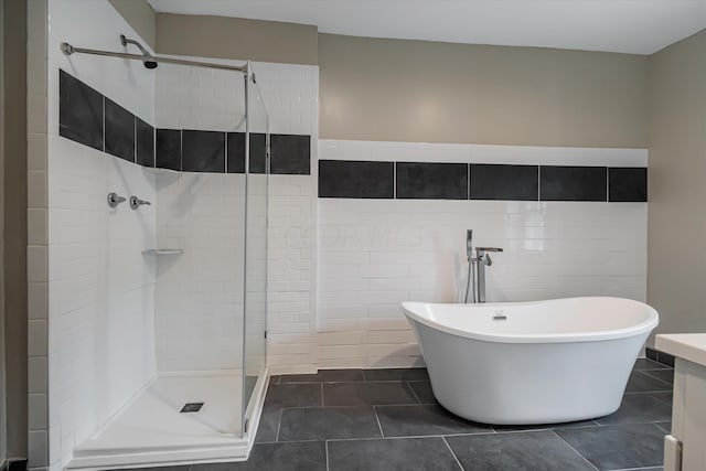 bathroom featuring tile patterned flooring, tile walls, and plus walk in shower