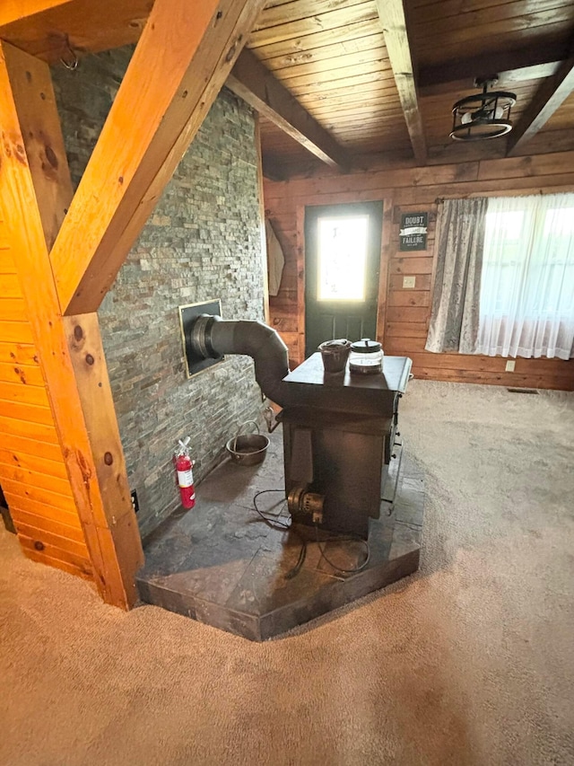 interior space featuring beam ceiling, carpet floors, and wood walls