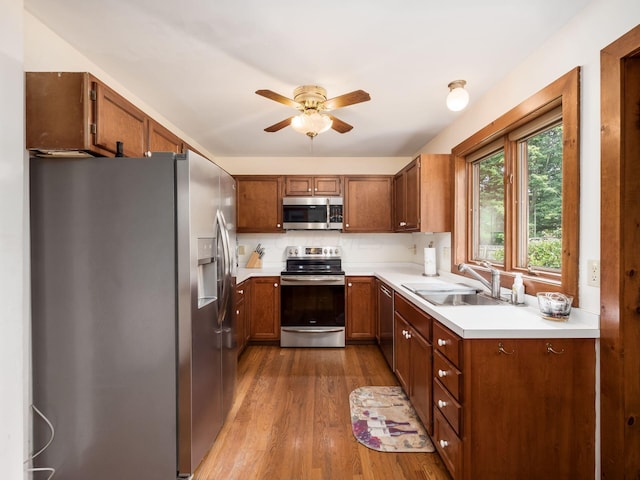 kitchen featuring ceiling fan, sink, decorative backsplash, appliances with stainless steel finishes, and hardwood / wood-style flooring