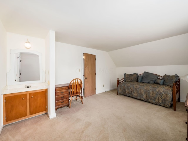 bedroom with ensuite bathroom, sink, light colored carpet, and vaulted ceiling