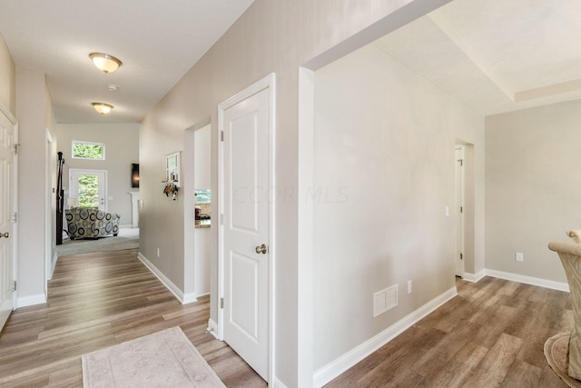 hall featuring lofted ceiling, a textured ceiling, and light wood-type flooring