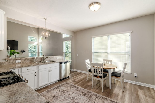 kitchen featuring stainless steel dishwasher, sink, decorative light fixtures, light hardwood / wood-style floors, and white cabinetry