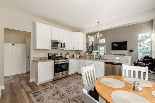 kitchen with dark hardwood / wood-style floors, decorative light fixtures, light stone counters, white cabinetry, and stainless steel appliances