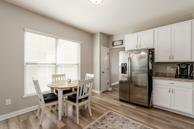 kitchen with stainless steel fridge with ice dispenser, white cabinets, a healthy amount of sunlight, and light wood-type flooring