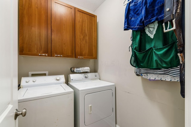 laundry area with washing machine and clothes dryer, cabinets, and a textured ceiling