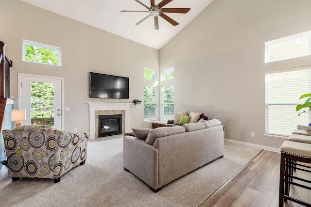 living room with a tile fireplace, a wealth of natural light, high vaulted ceiling, and light wood-type flooring