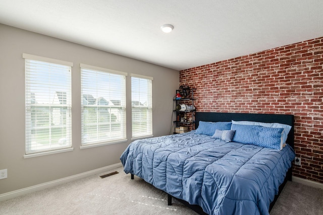 bedroom with carpet floors and brick wall