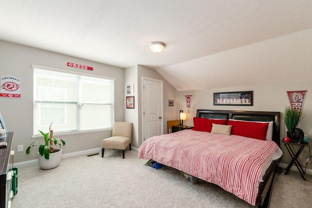 bedroom with a textured ceiling, carpet floors, and vaulted ceiling