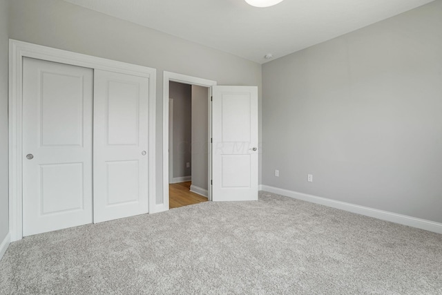 unfurnished bedroom featuring light carpet and a closet