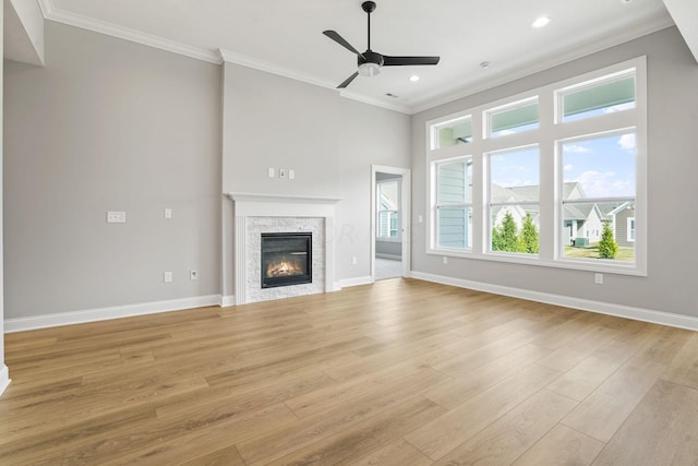 unfurnished living room with a stone fireplace, crown molding, and light hardwood / wood-style floors