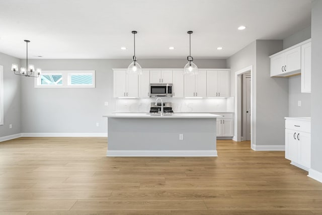 kitchen featuring white cabinetry, stainless steel appliances, and decorative light fixtures