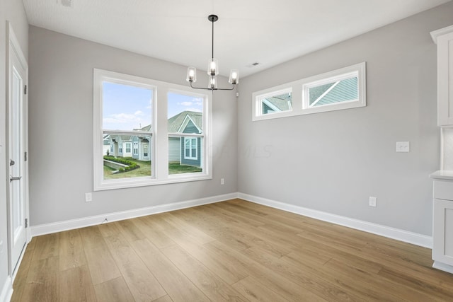 unfurnished dining area with light hardwood / wood-style floors and an inviting chandelier