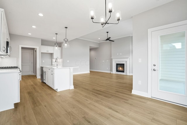 kitchen featuring white cabinetry, a center island with sink, pendant lighting, and light wood-type flooring