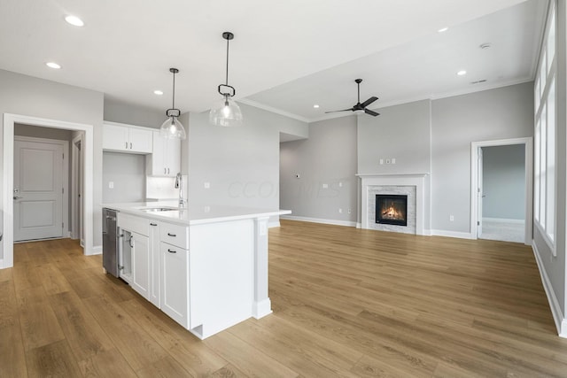 kitchen featuring sink, light hardwood / wood-style flooring, decorative light fixtures, a center island with sink, and white cabinets