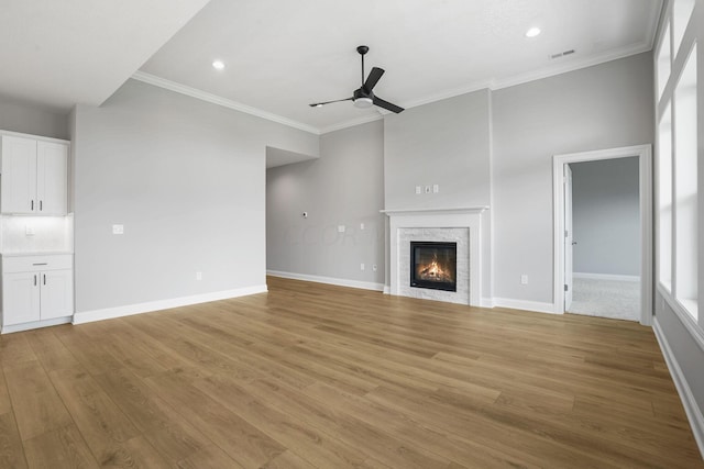 unfurnished living room featuring ceiling fan, light hardwood / wood-style floors, and ornamental molding