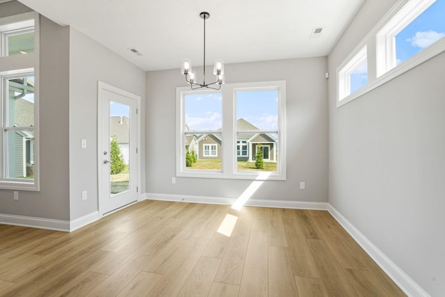 unfurnished dining area featuring light hardwood / wood-style floors, a wealth of natural light, and a chandelier