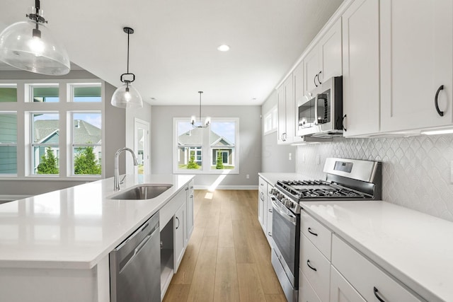 kitchen featuring white cabinets, sink, appliances with stainless steel finishes, and an island with sink