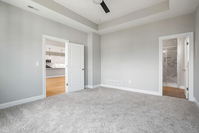 unfurnished bedroom featuring connected bathroom, carpet floors, and ceiling fan