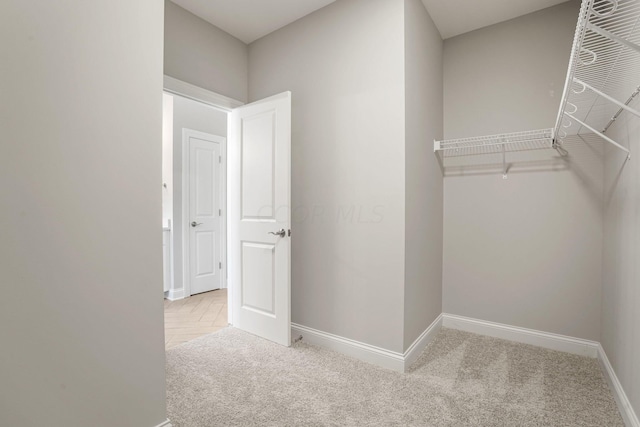 walk in closet with light carpet