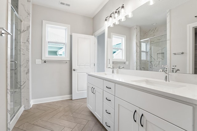 bathroom featuring vanity, a healthy amount of sunlight, and a shower with shower door