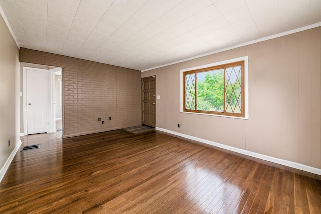 unfurnished room with hardwood / wood-style floors, brick wall, and ornamental molding