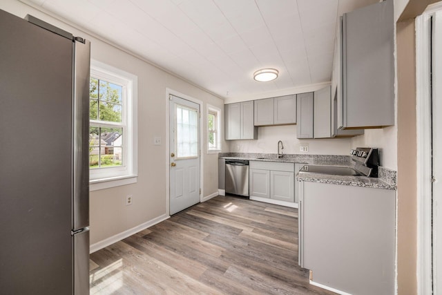 kitchen featuring stainless steel appliances, light hardwood / wood-style flooring, gray cabinetry, and sink