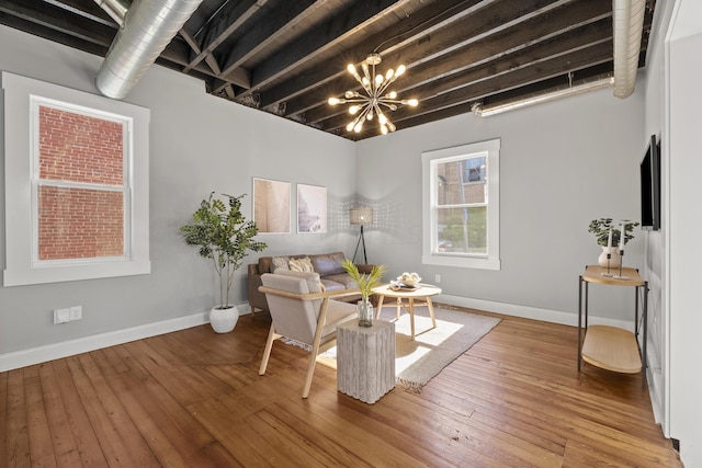 living area with wood-type flooring, an inviting chandelier, and beam ceiling