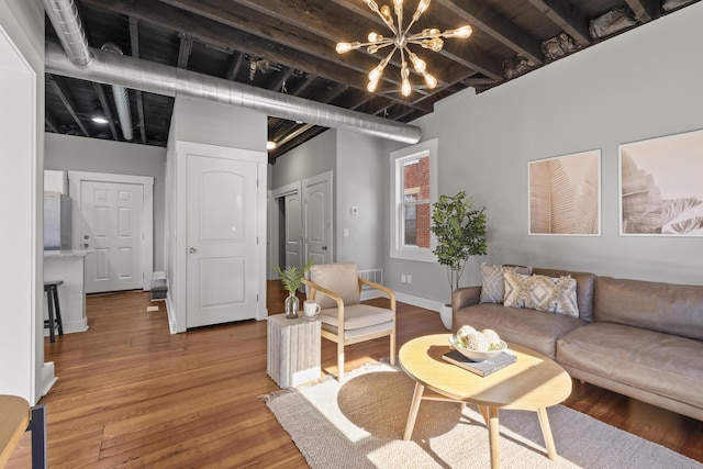 living room with beamed ceiling, a notable chandelier, and wood-type flooring