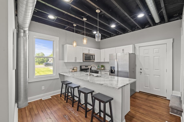 kitchen with dark hardwood / wood-style floors, light stone counters, white cabinetry, and stainless steel appliances