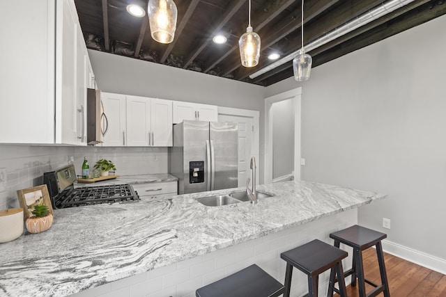 kitchen featuring stainless steel appliances, light stone counters, pendant lighting, a kitchen bar, and white cabinets