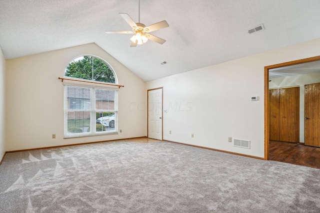 empty room with carpet flooring, a textured ceiling, vaulted ceiling, and ceiling fan