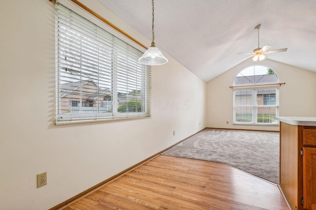 unfurnished dining area featuring light wood-type flooring, ceiling fan, and lofted ceiling