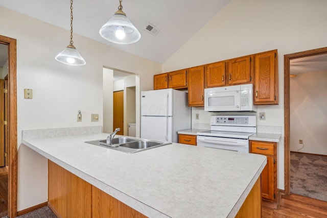 kitchen with kitchen peninsula, white appliances, sink, hanging light fixtures, and lofted ceiling