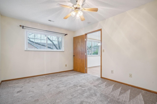 carpeted empty room featuring ceiling fan and a textured ceiling