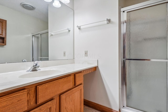 bathroom with a textured ceiling, vanity, and walk in shower