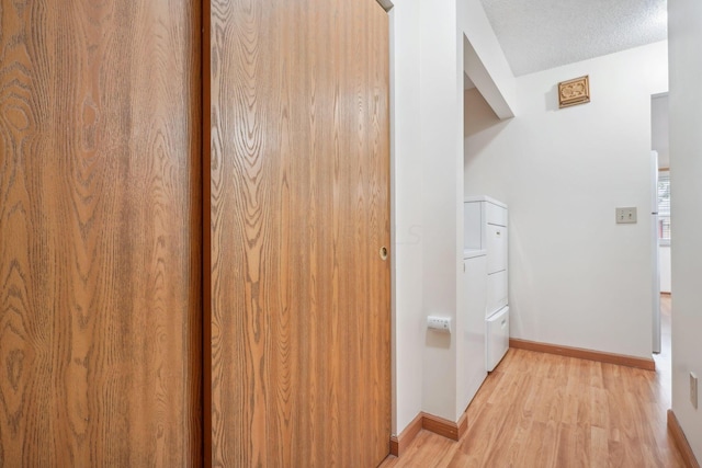 hall featuring a textured ceiling, light hardwood / wood-style floors, and lofted ceiling