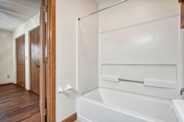 bathroom featuring wood-type flooring, a textured ceiling, and shower / tub combination