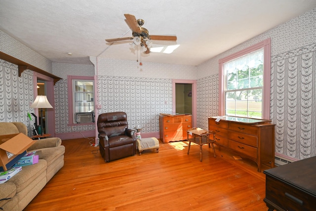 living room with ceiling fan, cooling unit, wood-type flooring, and a textured ceiling