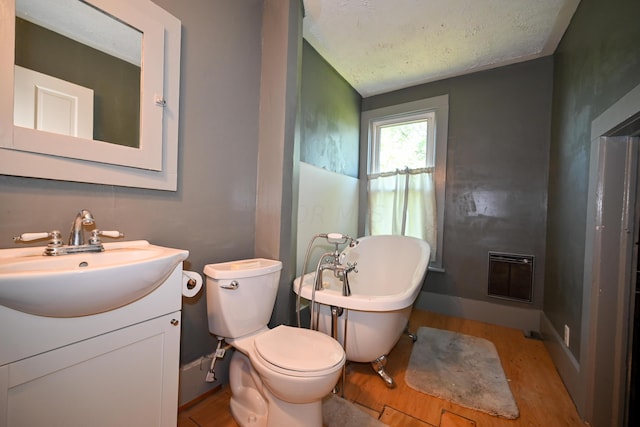 bathroom with a bathtub, vanity, toilet, a textured ceiling, and wood-type flooring