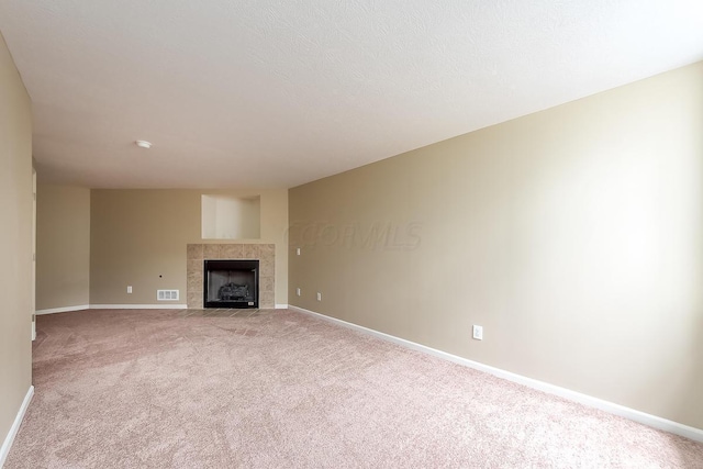 unfurnished living room featuring light colored carpet and a tile fireplace