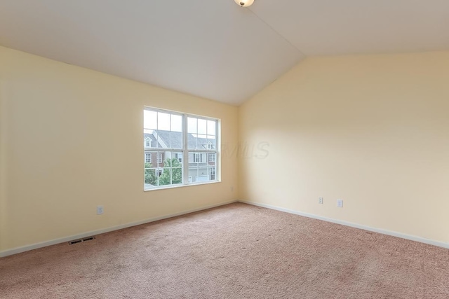 carpeted spare room featuring vaulted ceiling