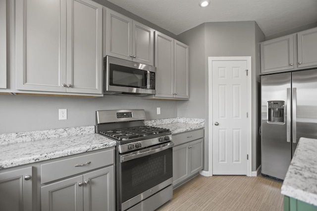 kitchen featuring gray cabinetry, light stone counters, and stainless steel appliances