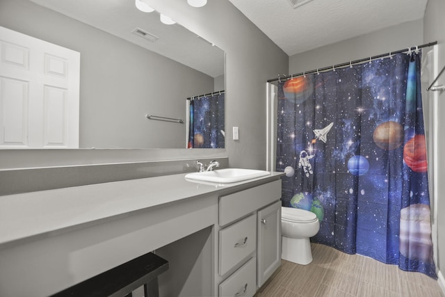 bathroom featuring vanity, toilet, and a textured ceiling