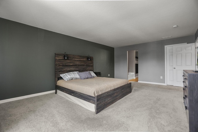 carpeted bedroom with a textured ceiling and ensuite bathroom