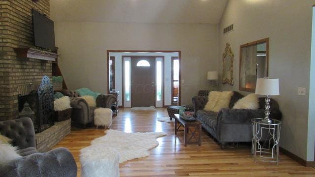 living room with light hardwood / wood-style floors, a fireplace, and vaulted ceiling