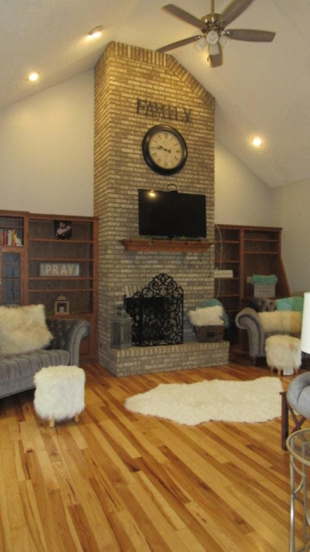 living room featuring ceiling fan, a fireplace, vaulted ceiling, and hardwood / wood-style flooring