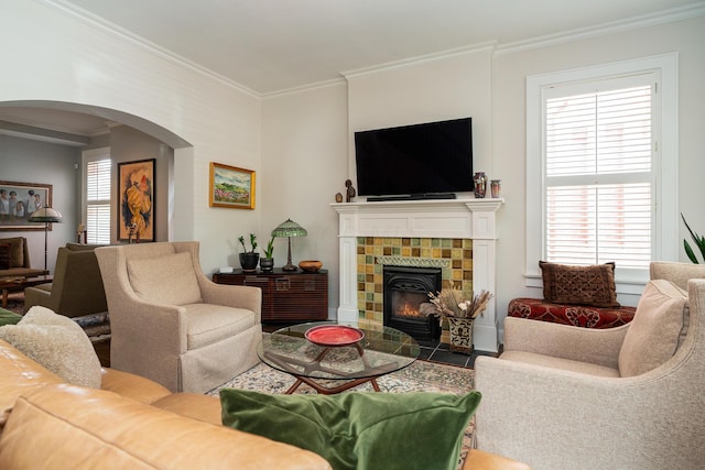 living room featuring crown molding, a healthy amount of sunlight, and a tiled fireplace