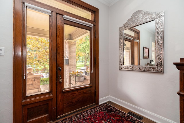 doorway to outside featuring crown molding, a wealth of natural light, and wood-type flooring