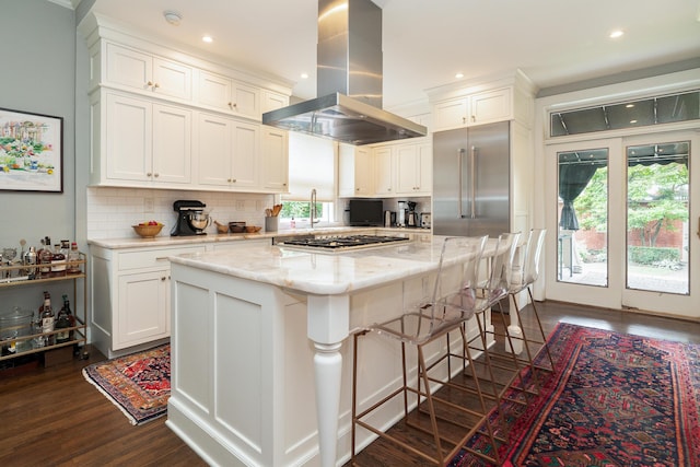 kitchen featuring a kitchen island, island range hood, white cabinets, dark hardwood / wood-style flooring, and stainless steel appliances